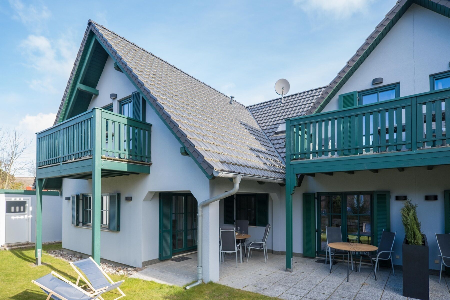 A two-story house with a balcony, a patio with outdoor seating, and a satellite dish.