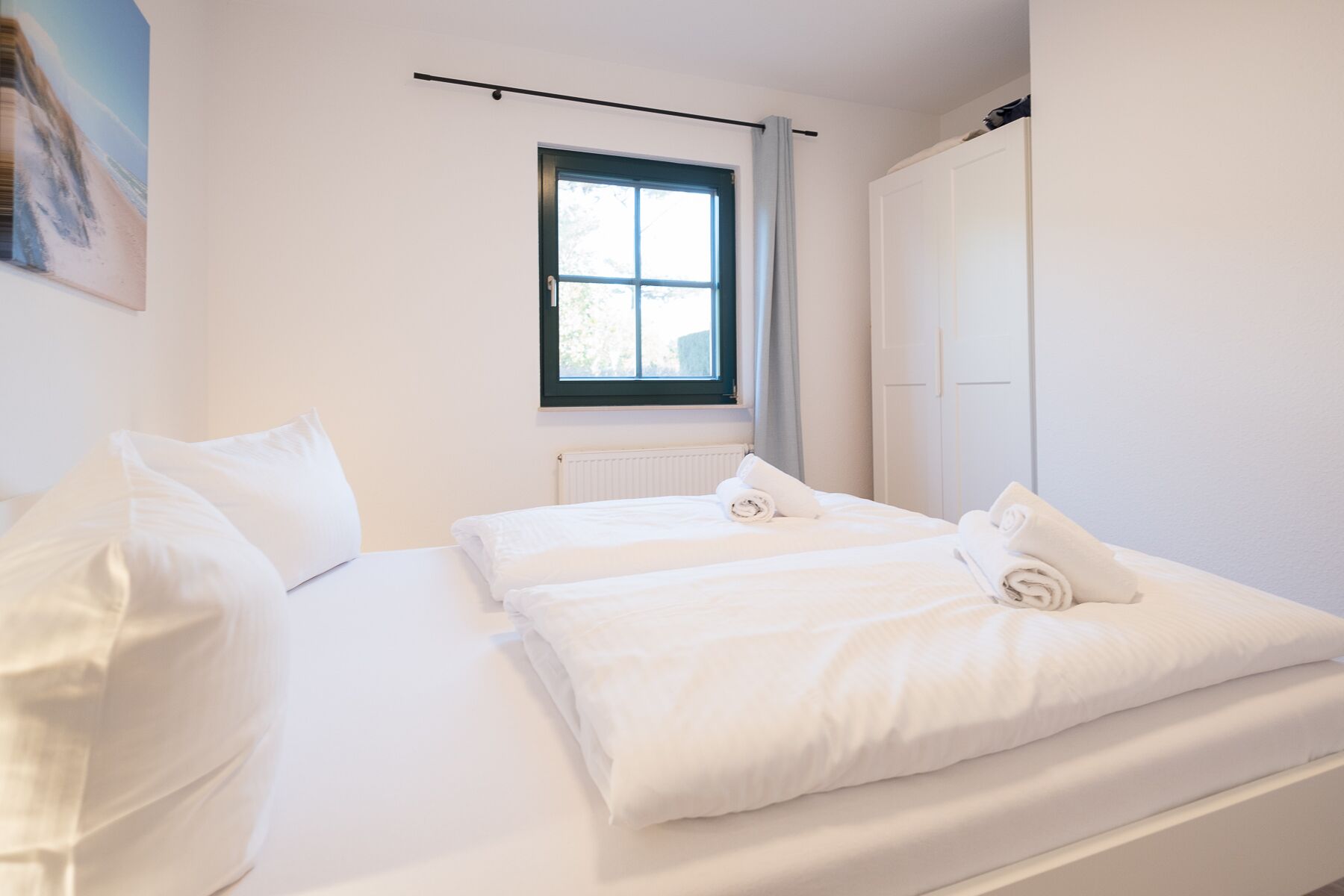 Une chambre à coucher avec un lit, des oreillers, une fenêtre et un radiateur.