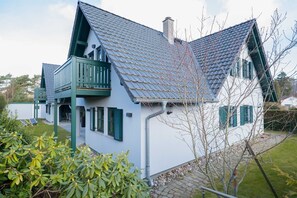 A two-story house with a steeply pitched roof, a balcony, and a small garden area. - First floor apartment Lee Ost 2.1 in Ostseebad Dierhagen (Ostseebad Dierhagen)