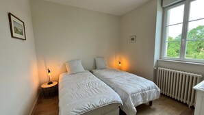 Ein Schlafzimmer mit zwei Betten, einem Fenster und einer Heizung.