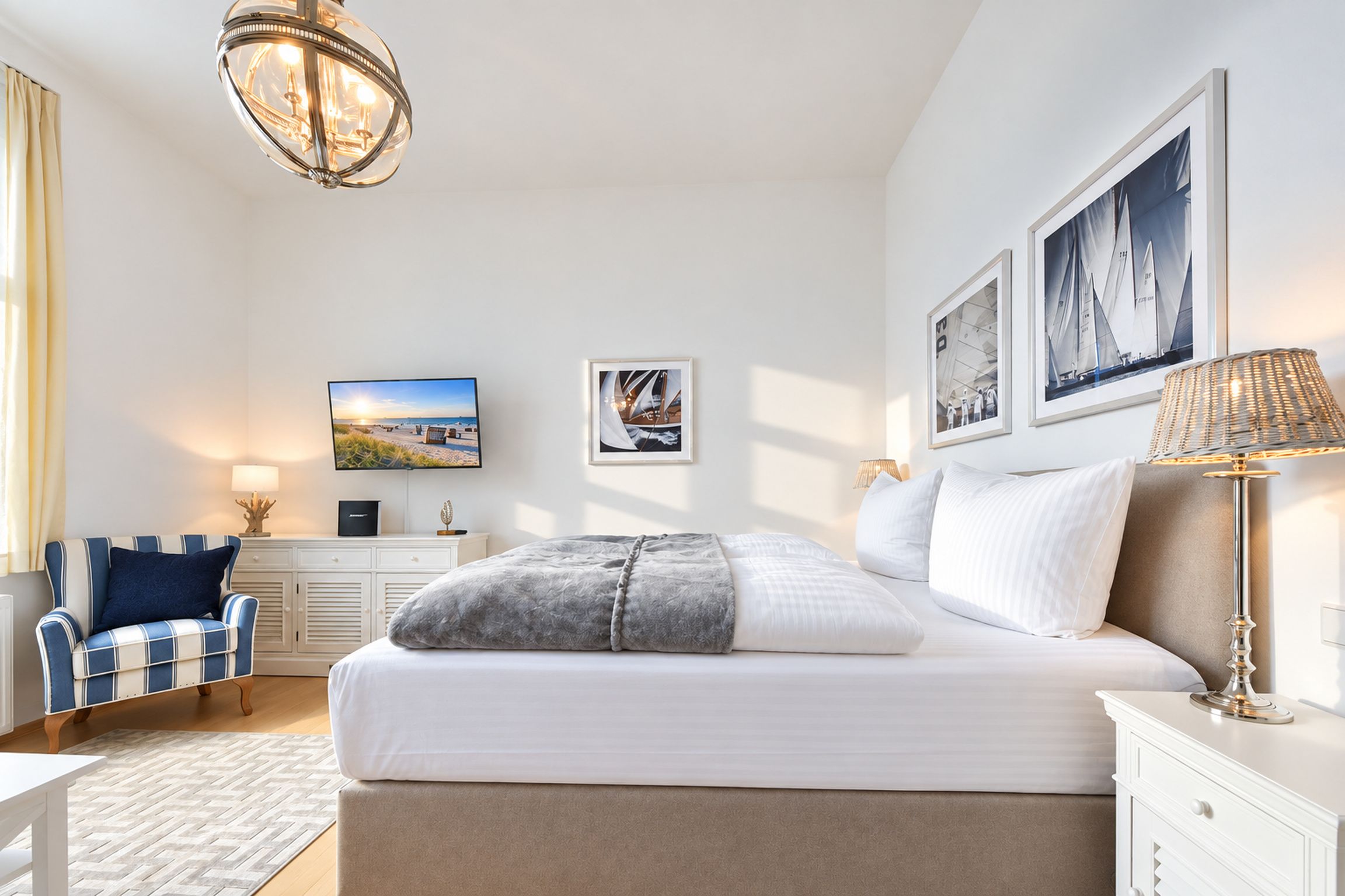 Ett hotellrum med en säng, en stol, ett skrivbord, en lampa och konstverk på väggarna.