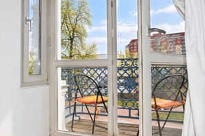 Ein Zimmer mit Blick auf einen Baum und Gebäude durch ein Fenster mit einem Metallgitter.