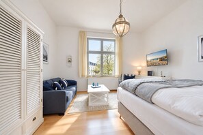 Une chambre à coucher comprenant un lit, un canapé, une table, une fenêtre avec vue et un luminaire suspendu.