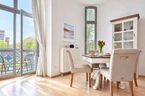 Un espace repas comprenant une table, des chaises, un buffet et donnant sur l’extérieur.