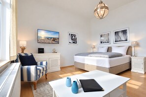 Ein Hotelzimmer mit Bett, Schreibtisch, Stuhl und Fenster.