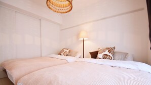 A double bed with a textured blanket, a bedside lamp, and patterned pillows. - Mishuku Onna102 (Onna)