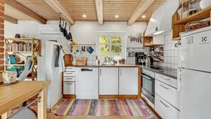 Una cocina moderna con armarios blancos, techo de madera y un ventanal grande.