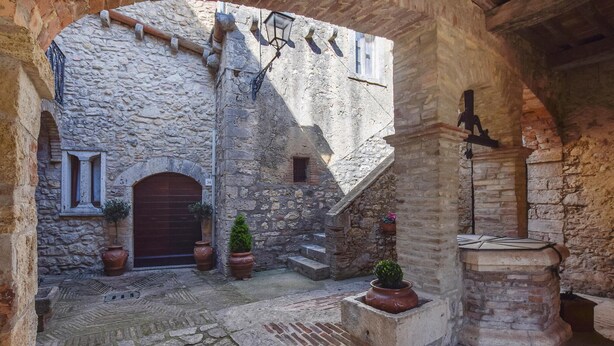 A stone courtyard with a wooden door, potted plants, and a stone bench. - Nice apartment in Civitella del Lago with WiFi (Civitella del Lago)