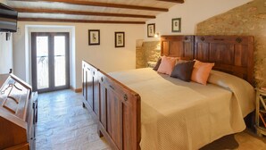 A bedroom with a large bed, wooden headboard, stone wall, and a door leading to a balcony. - Nice apartment in Civitella del Lago with WiFi (Civitella del Lago)