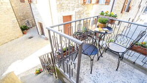 A balcony with a metal railing, a small round table with chairs, and potted plants. - Nice apartment in Civitella del Lago with WiFi (Civitella del Lago)
