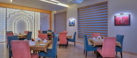 A restaurant with tables set for dining, featuring a modern interior with decorative lighting and artwork on the walls.