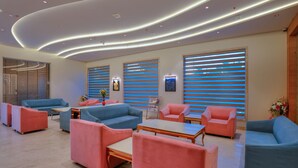 Un área de estar moderna con sofás, sillones, una mesa de centro y una recepción.