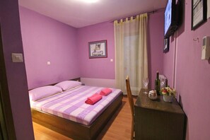 Un dormitorio con una cama, una mesita con una botella y un vaso, y una silla.