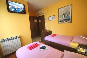 Habitación de hotel con dos camas, televisor, un cuadro enmarcado y un minibar.