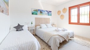 Une chambre avec deux lits, une tête de lit en bois, une table de chevet, une fenêtre avec vue et des œuvres d’art mural.