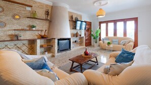 Un salon avec une cheminée, des canapés, un téléviseur et des objets de décoration.