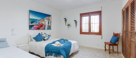 Une chambre à coucher avec un lit, une chaise, une fenêtre et un tableau accroché au mur.