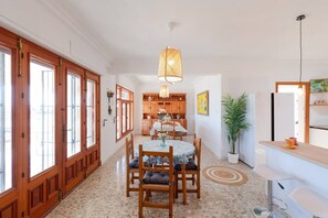 A spacious kitchen with wooden cabinets, a dining area with a round table, and a bar area. - Fidalsa Imperial Malibu (Elx)