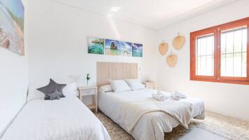 Une chambre d’hôtel avec deux lits, une grande fenêtre et des œuvres d’art murales.