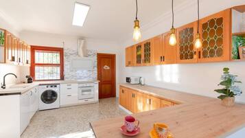 Une cuisine moderne dotée d’un lave-linge encastré, de meubles en bois et d’un plan de travail en bois.