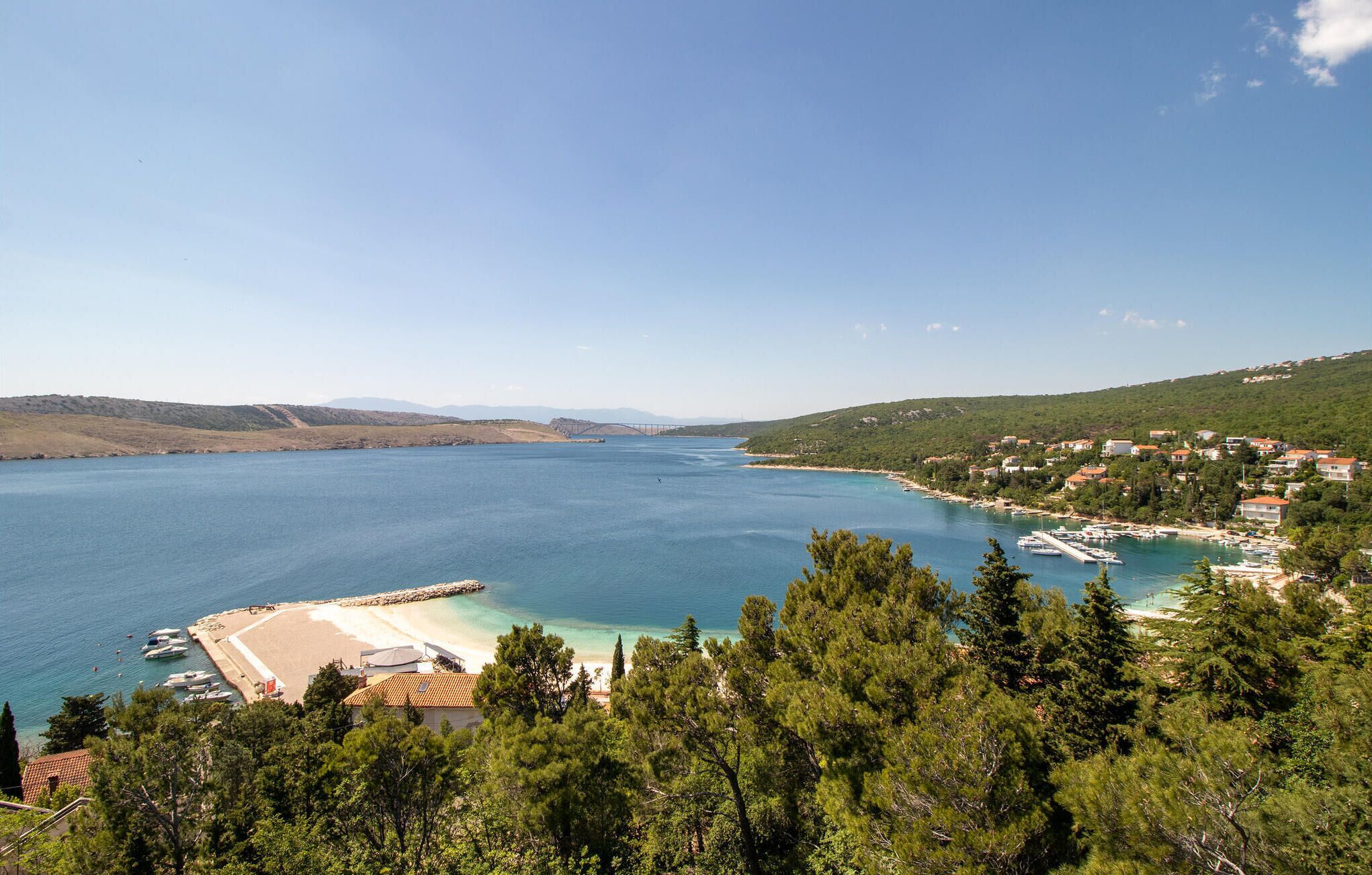 A coastal town with a marina, sandy beach, and residential buildings.
