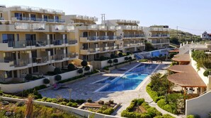 Un hôtel à plusieurs étages doté de balcons, d’une piscine et de jardins aménagés.