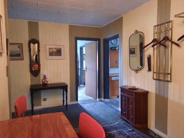 A dining area with a wooden table and chairs, a console table with a vase, and a mirror on the wall. - Living in a mansion built in 1848 in the Fichtelgebirge (Ebnath)