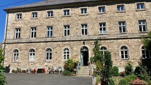 A stone building with multiple windows and a central entrance. - Living in a stately home from 1848 in the Fichtelgebirge (Ebnath)