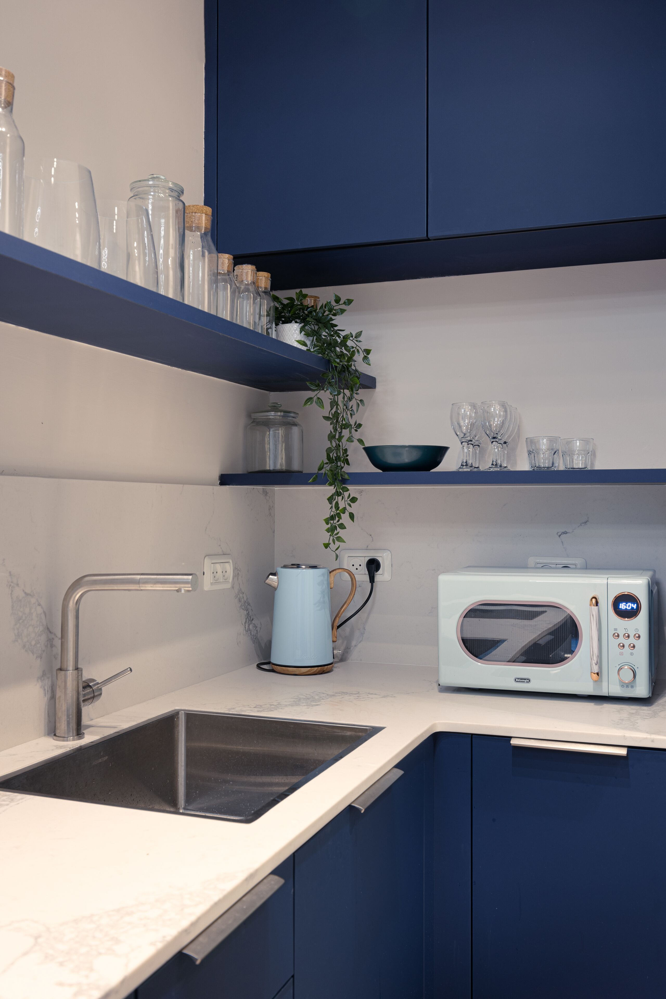 A kitchen with a sink, a microwave, and blue cabinets.