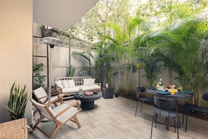 Une terrasse avec un canapé, des chaises, une table ronde et un ventilateur.