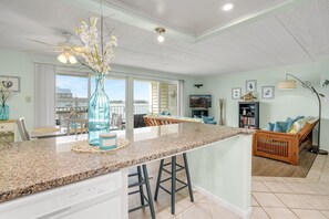 A spacious kitchen with a granite countertop, a central island with stools, and a view of the outside.