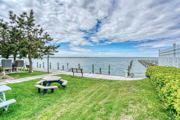 A waterfront park with picnic tables, benches, and a walking path along the water.
