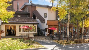 Un edifici modern amb una zona de cafeteria i seients a l'aire lliure amb paraigües vermells.