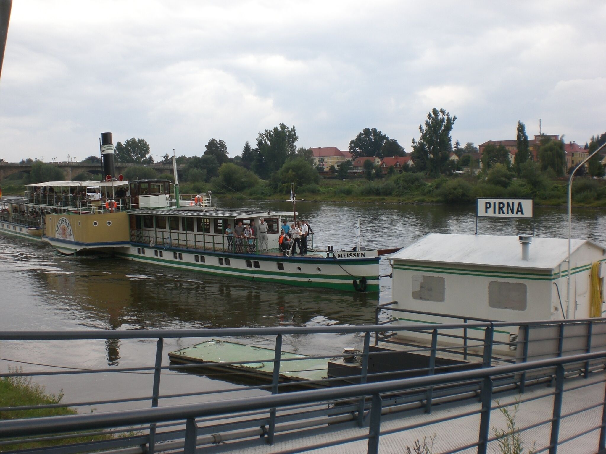 A riverboat with a sign reading 'PIRNA' docked at a pier.