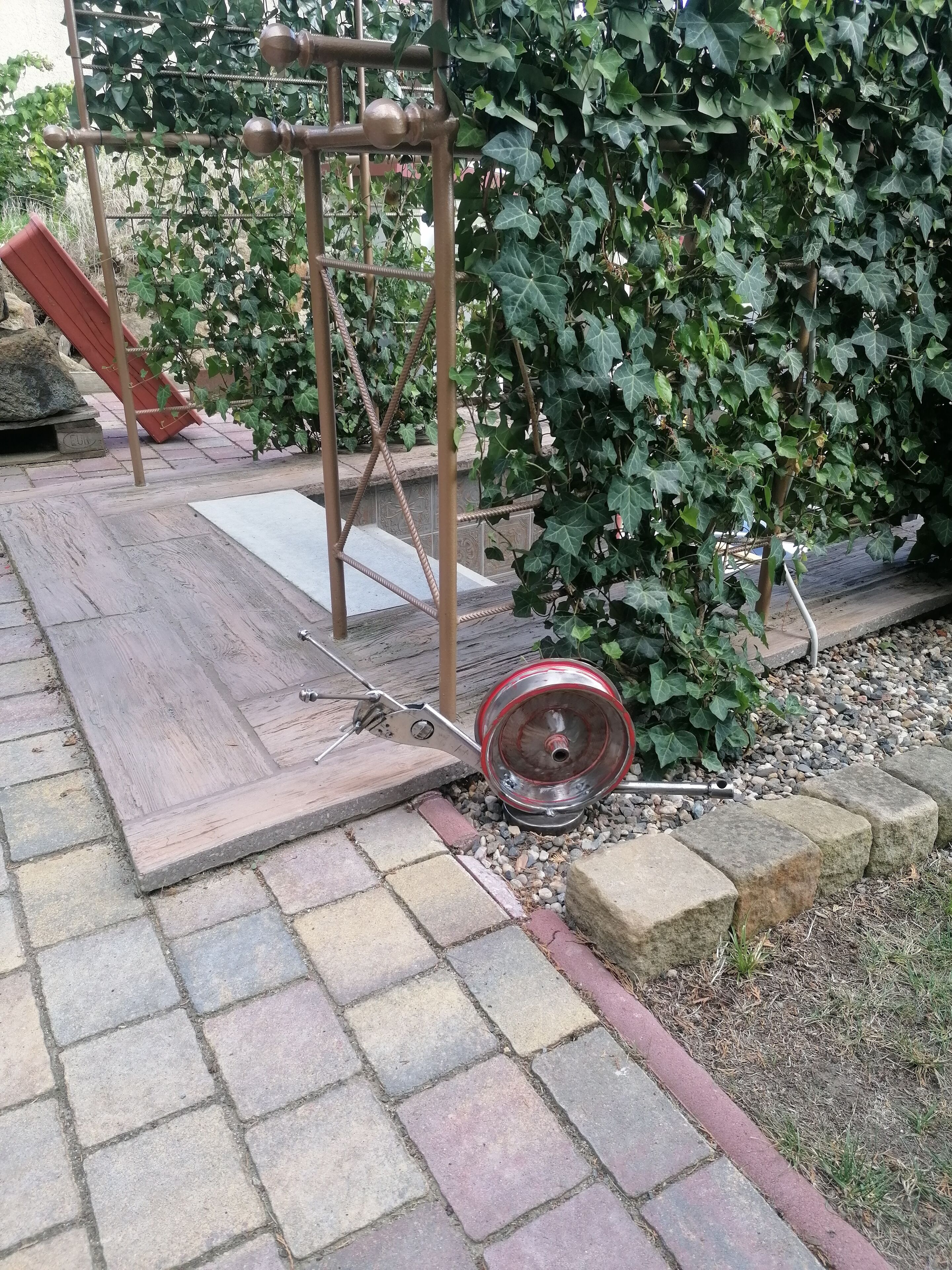 Um jardim com um deck de madeira, uma estrutura de metal e um escorrega vermelho.