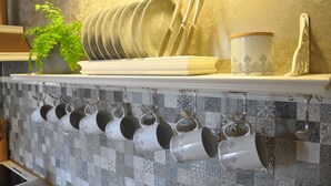 Een keuken met een witte plank waarop borden, bekers en bestek staan.
