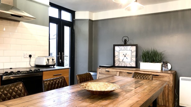 A modern kitchen with a wooden dining table, a stove, and a large window. - Short summer breaks available!! (St Davids)