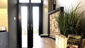 A reception area with a wooden floor, a black-framed clock, and a sign for 'stay st. davids'. - Short summer breaks available!! (St Davids)