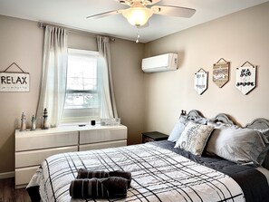 A bedroom with a bed, a ceiling fan, a window with curtains, a dresser, and wall decorations. - The Lighthouse- Gameroom, RooftopDeck! Beach badges,chairs,cart incld (Seaside Heights)
