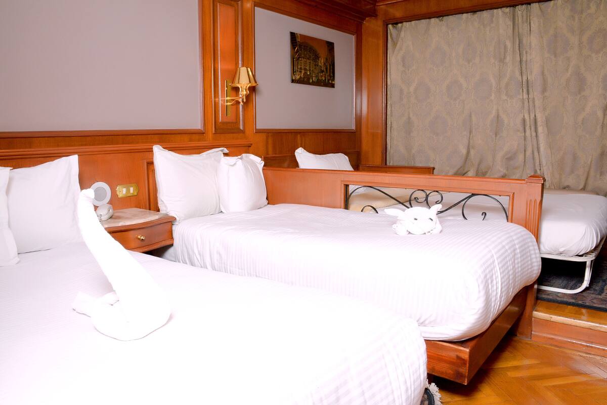 Une chambre d’hôtel avec deux lits, une table de chevet, une lampe et un tableau au mur.