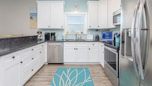 Eine moderne Küche mit weißen Schränken, Edelstahlgeräten und einer blauen Spritzschutzwand.
