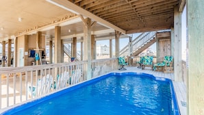 Ein Innenpool mit Holzterrasse, Stühlen und einer Treppe zu einer erhöhten Ebene.