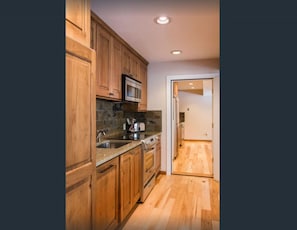 Kitchen features a microwave, toaster, and sink, with adjacent access to a hallway.