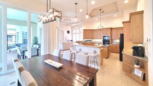 A spacious kitchen with wooden cabinets, a central island, and a dining area with a large wooden table and chairs. - Marco Island Waterfront Home w/Heated Pool, Bikes, < 2 Miles to the Beach (Marco Island)
