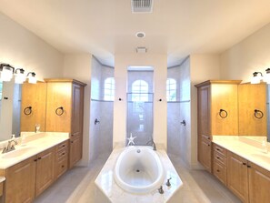 A spacious bathroom with a large bathtub, two sinks, wooden cabinets, and a large window. - Marco Island Waterfront Home w/Heated Pool, Bikes, < 2 Miles to the Beach (Marco Island)
