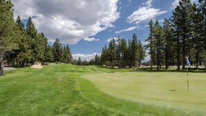 Un terrain de golf avec un ciel dégagé, de l’herbe verte et des arbres.