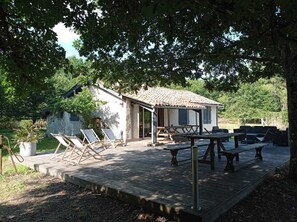 A rustic cabin with a patio area featuring lounge chairs and a wooden deck.
