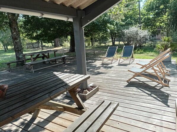 A wooden deck with a picnic table and lounge chairs.