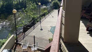 Een balkon met uitzicht op een rivier, zitplaatsen buiten en een barbecue.