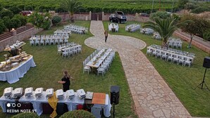 Evento ao ar livre com mesas montadas para refeições, palco e uma paisagem deslumbrante de montanhas e vegetação.